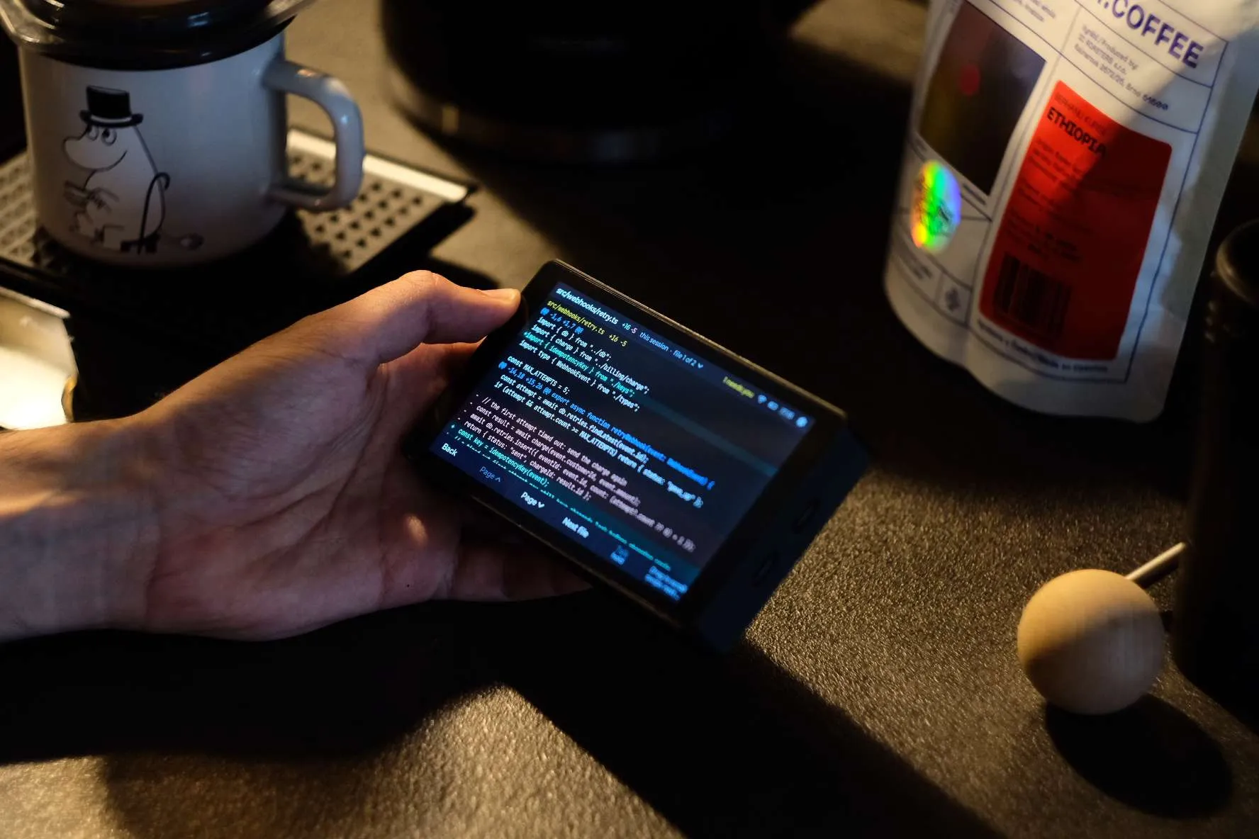 A hand holding the board, which shows a code diff of src/webhooks/retry.ts with added and removed lines.